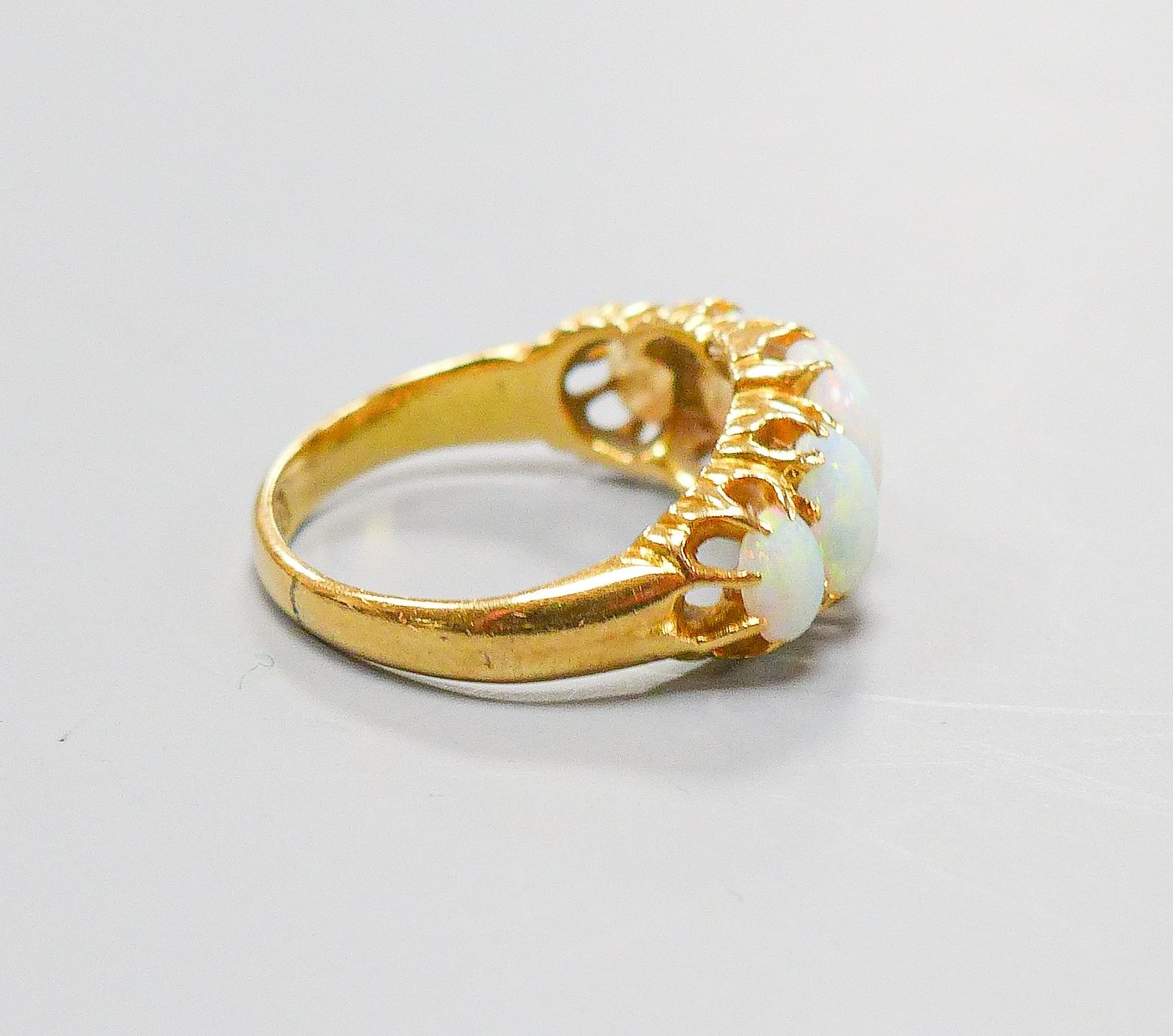 An Edwardian 18ct gold and graduated five stone white opal set half hoop ring, size K, gross 3.8 grams.